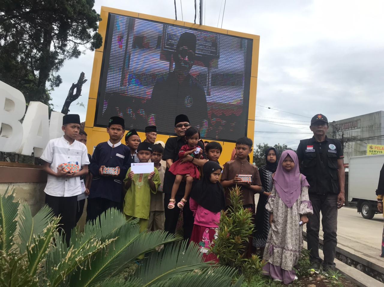 Anggota DPRD Kabupaten Sukabumi Fraksi Gerindra Ade Dasep Zaenal Abidin saat mengajak anak yatim berfoto bersama didepan Layar Videotron Murotal Alquran di Kecamatan Cikembar.